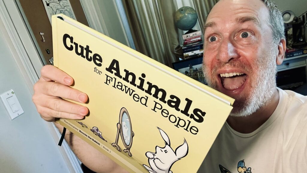 Porter Mason holding up his book Cute Animals for Flawed People, The Complete Roonie the Rabbit, Book 1